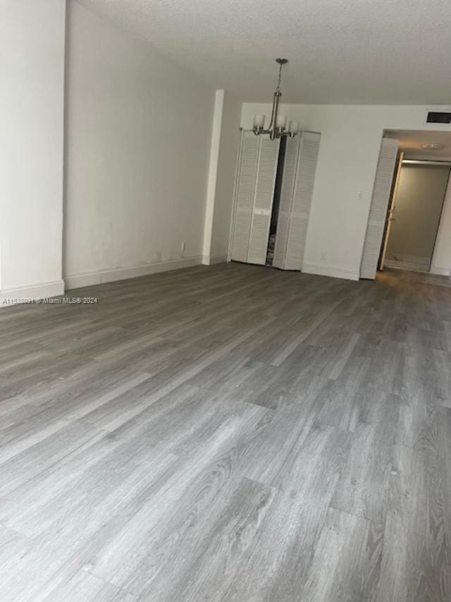 empty room with a notable chandelier and hardwood / wood-style floors