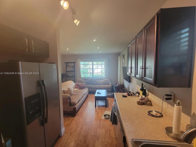 kitchen featuring sink, dark brown cabinets, light hardwood / wood-style flooring, and stainless steel fridge