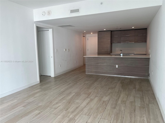 unfurnished living room featuring sink and light wood-type flooring