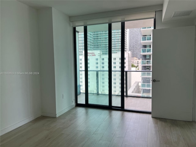 unfurnished room featuring plenty of natural light, light wood-type flooring, and a wall of windows