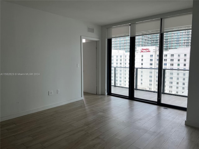 empty room featuring a wall of windows and hardwood / wood-style flooring