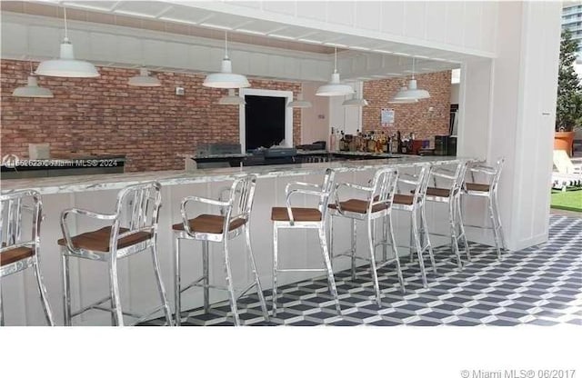 bar featuring white cabinets, light stone counters, decorative light fixtures, and dark tile flooring