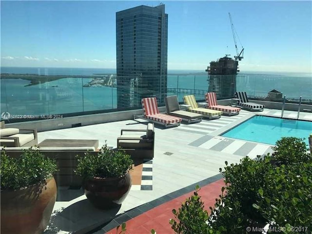 view of pool featuring a water view and a patio