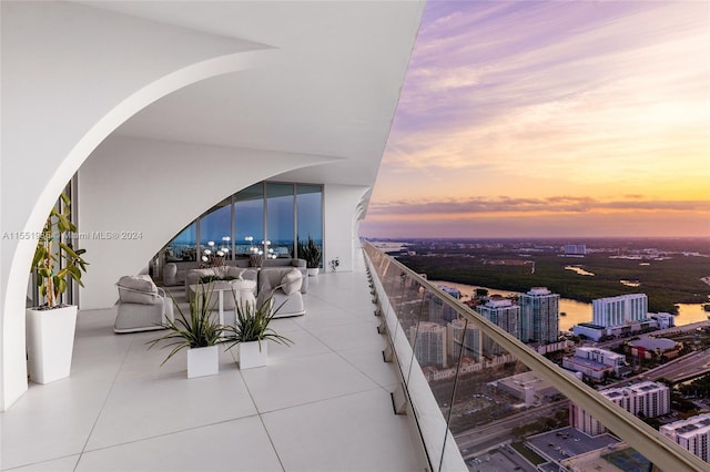 balcony at dusk with a water view and a view of city