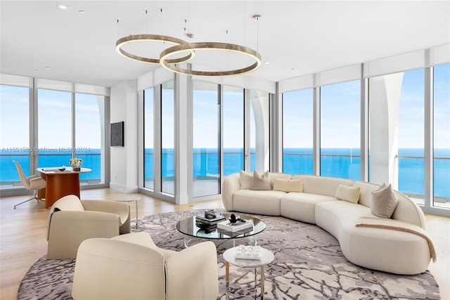 living room featuring light hardwood / wood-style floors, a wall of windows, and a water view