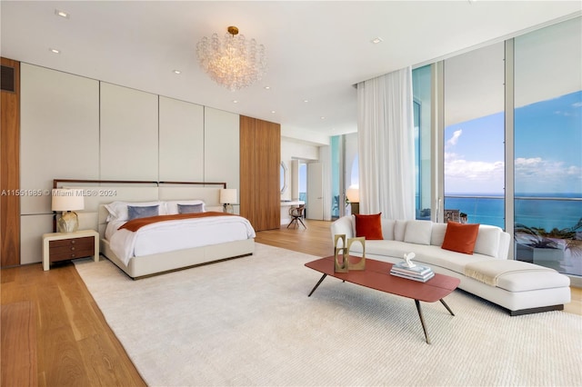 bedroom featuring a water view, light hardwood / wood-style flooring, expansive windows, and multiple windows