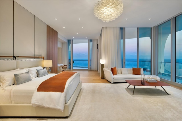 bedroom featuring expansive windows, a water view, light wood-type flooring, and access to exterior