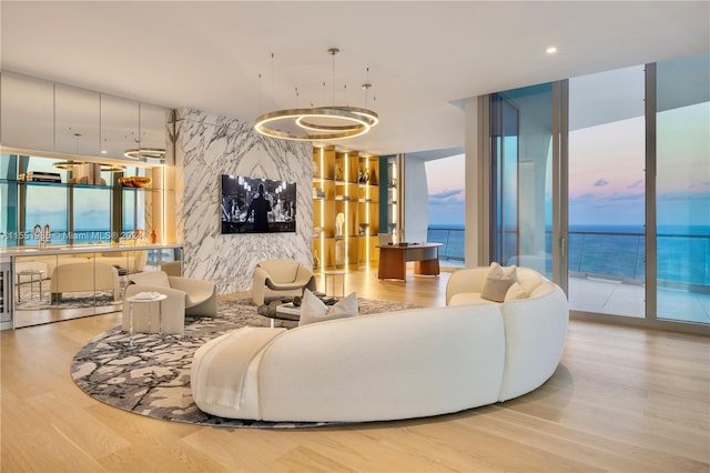 living room featuring light hardwood / wood-style flooring, expansive windows, and a water view