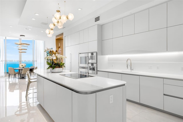 kitchen featuring light tile floors, a kitchen island, white cabinets, sink, and decorative light fixtures