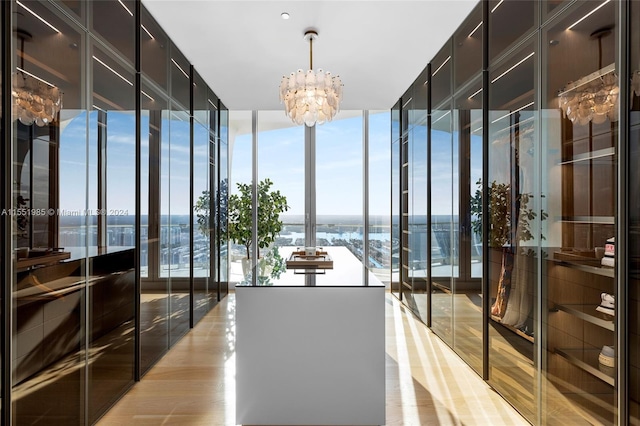 interior space featuring a notable chandelier, light hardwood / wood-style floors, and expansive windows