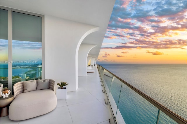 balcony at dusk featuring a water view