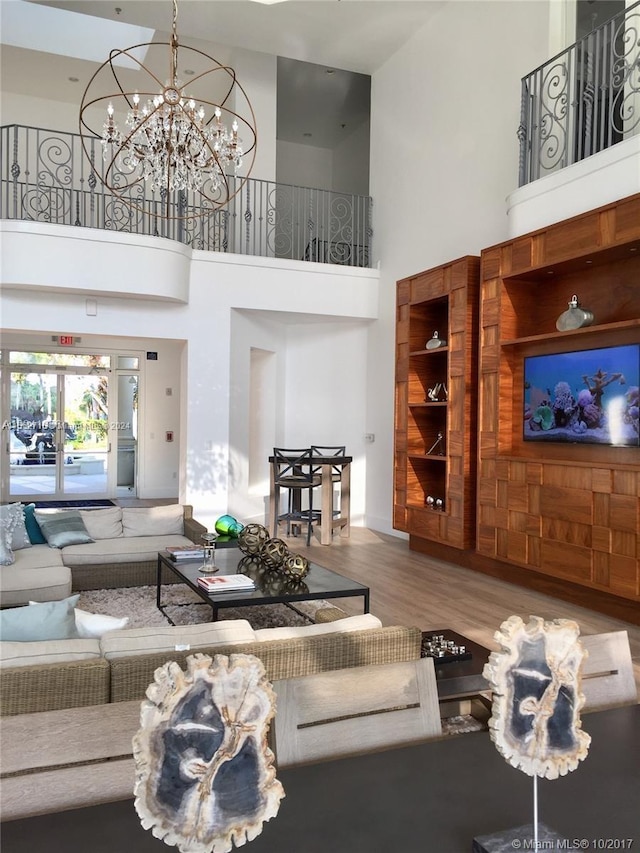 living room with a chandelier, hardwood / wood-style floors, and a towering ceiling