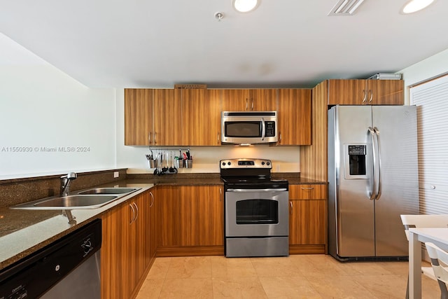 kitchen featuring dark stone countertops, light tile flooring, appliances with stainless steel finishes, and sink