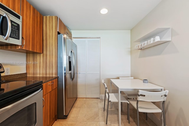 kitchen with stainless steel appliances, light tile floors, and dark stone counters