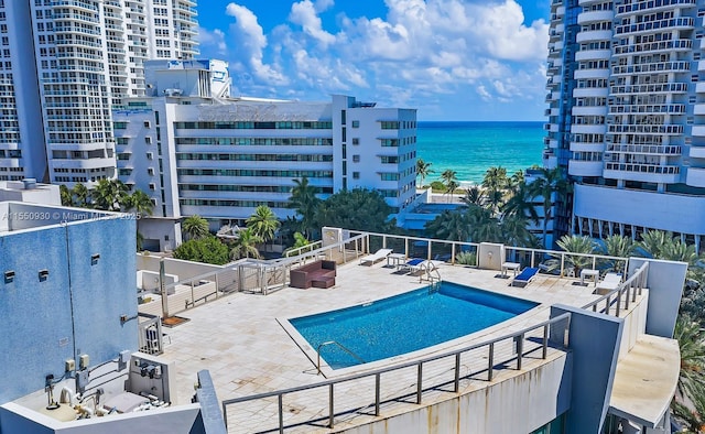 pool featuring a patio, fence, and a water view