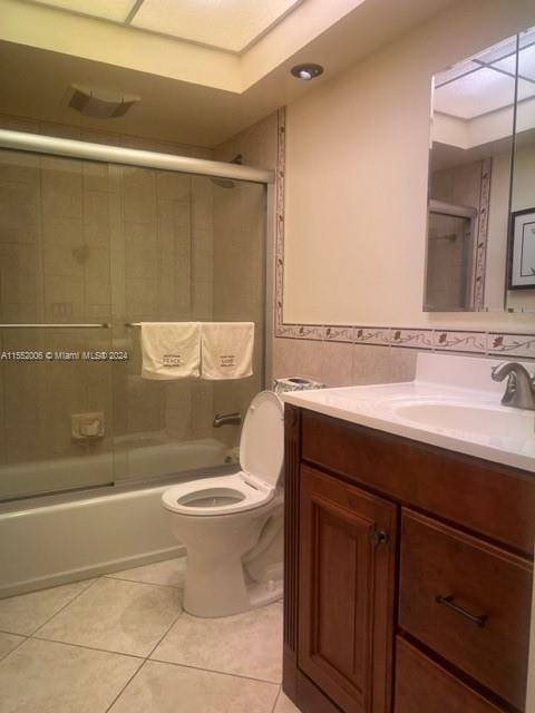 full bathroom featuring tile floors, enclosed tub / shower combo, toilet, and vanity