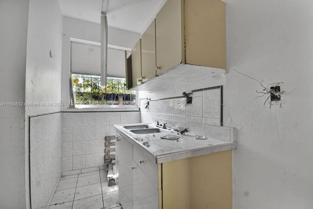 kitchen with tile walls, sink, cream cabinetry, backsplash, and light tile flooring