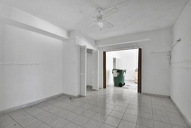 spare room featuring a textured ceiling, ceiling fan, and light tile floors