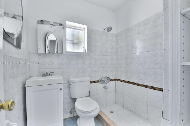 bathroom with vanity, tile walls, tiled shower, tile flooring, and toilet