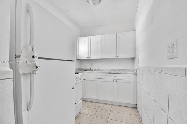 kitchen with white cabinetry, light tile flooring, tile walls, tasteful backsplash, and white refrigerator