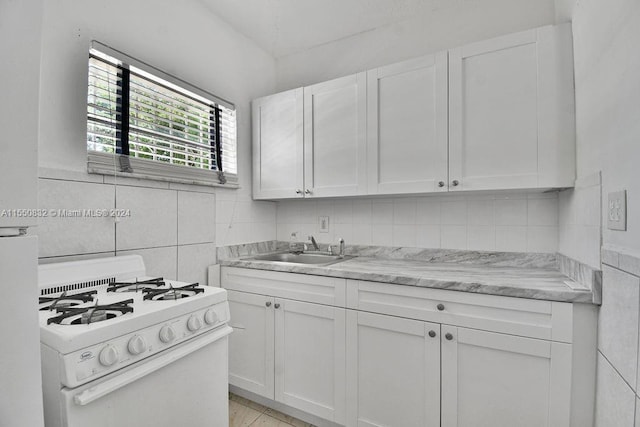 kitchen featuring backsplash, sink, white cabinetry, and white range