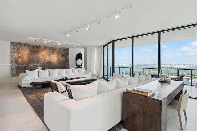 living room with floor to ceiling windows, a water view, and track lighting