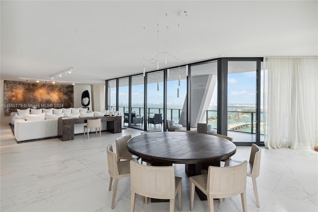 tiled dining room with floor to ceiling windows, rail lighting, and a water view