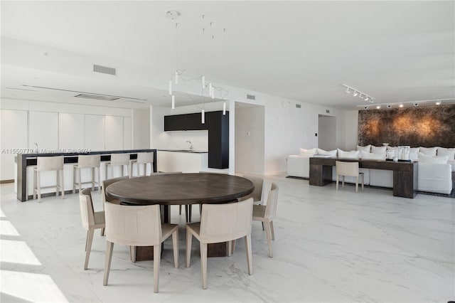 tiled dining room featuring rail lighting and sink