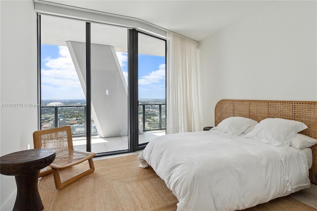 bedroom featuring access to exterior, floor to ceiling windows, and light wood-type flooring