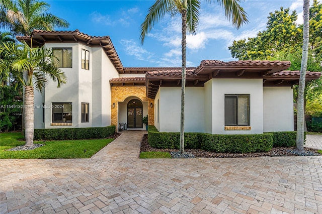 mediterranean / spanish-style home with french doors and a front lawn