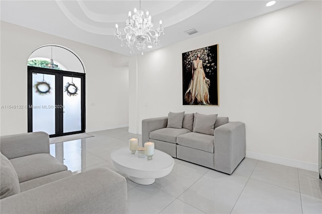 living room with french doors, light tile flooring, a notable chandelier, and a tray ceiling