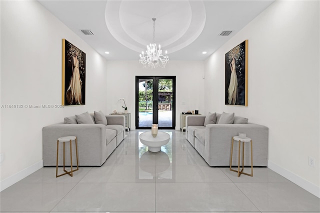 tiled living room with an inviting chandelier, a tray ceiling, and french doors