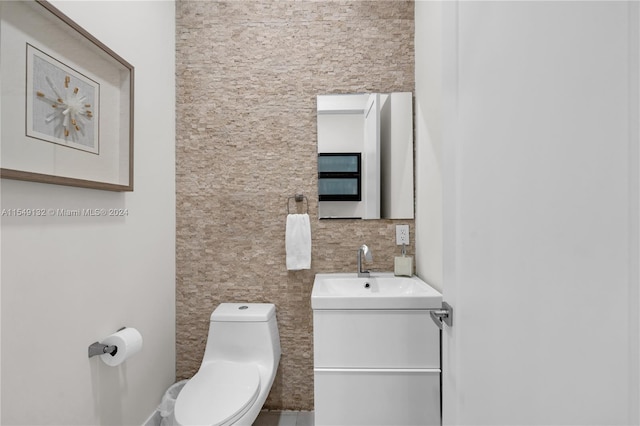 bathroom with toilet, vanity, and tile walls