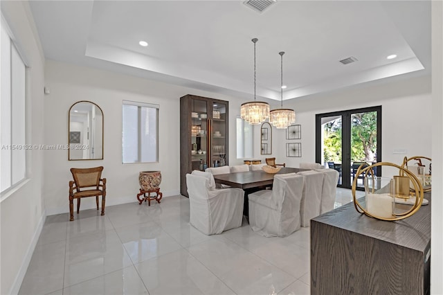 tiled dining area featuring an inviting chandelier and a tray ceiling