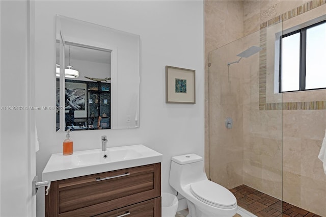 bathroom featuring toilet, a tile shower, and vanity with extensive cabinet space