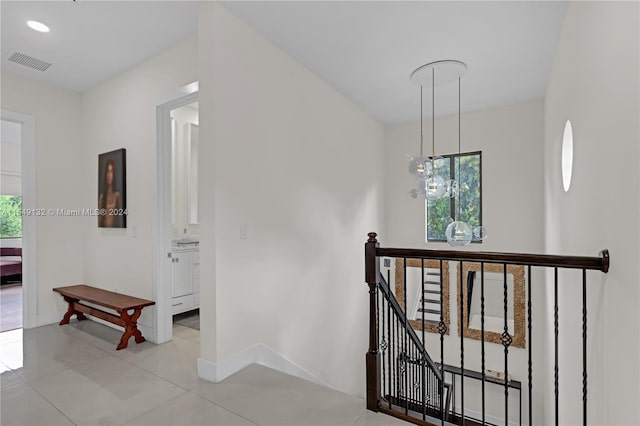 corridor with a notable chandelier and light tile floors