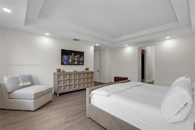 bedroom featuring a tray ceiling and light hardwood / wood-style flooring