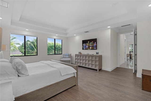 bedroom with a tray ceiling and light hardwood / wood-style flooring