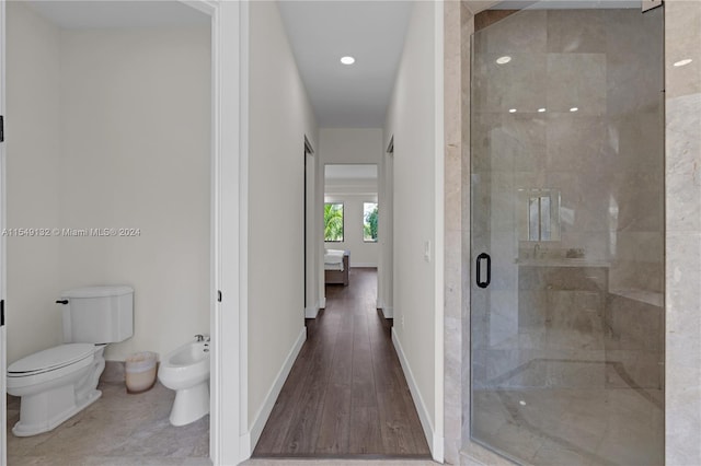 bathroom featuring toilet, a bidet, a shower with shower door, and hardwood / wood-style flooring