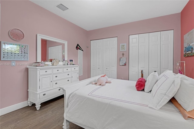 bedroom featuring two closets and hardwood / wood-style floors