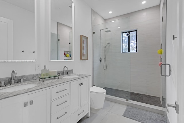 bathroom with toilet, double vanity, tile floors, and a shower with shower door