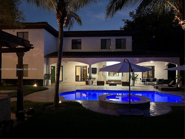 pool at night featuring a patio area