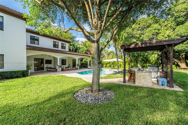 view of swimming pool featuring a patio, a yard, and exterior kitchen