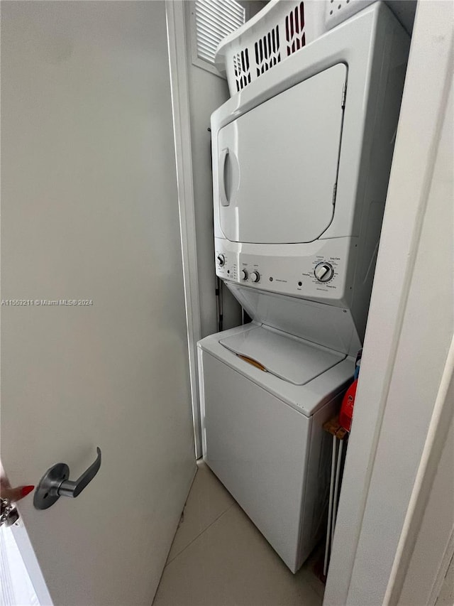 clothes washing area with stacked washer / drying machine and light tile floors