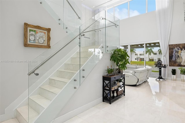 staircase featuring light tile flooring and a high ceiling