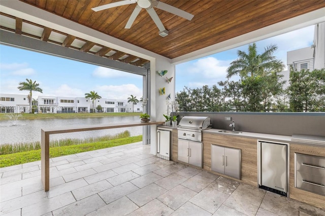 view of patio featuring sink, ceiling fan, exterior kitchen, a grill, and a water view