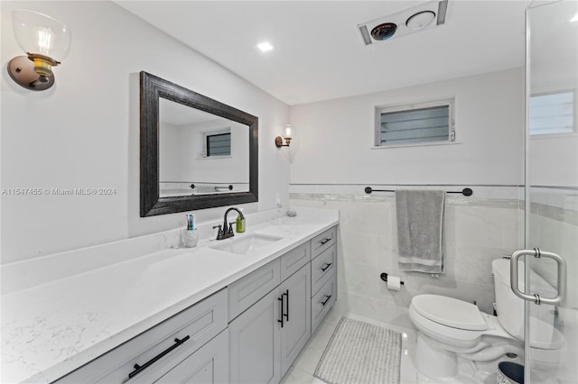 bathroom featuring tile flooring, tile walls, vanity, and toilet