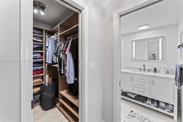 walk in closet featuring light tile floors and sink