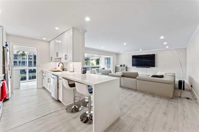 kitchen with a kitchen bar, crown molding, light wood-type flooring, and white cabinetry