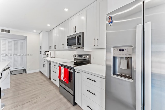 kitchen featuring white cabinets, light hardwood / wood-style flooring, stainless steel appliances, and beverage cooler